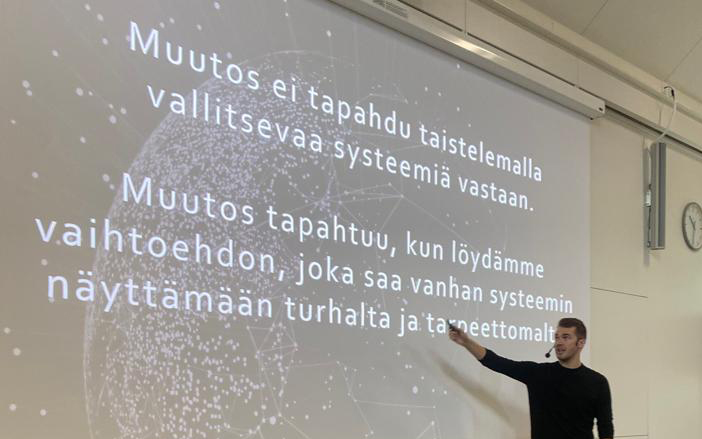 mies osoittaa screenillä olevaa kuvaa ja selittää yleisölle