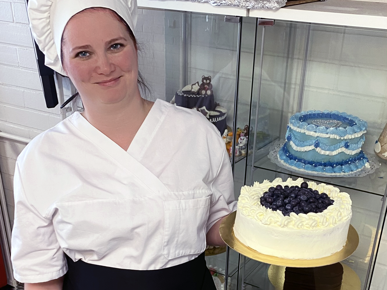 Kondiittori-opiskelija esittelee tekemäänsä kermakakkua