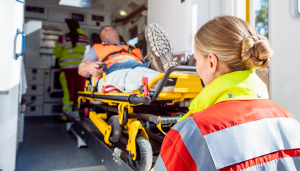 ensihoitaja nostaa paareilla olevan asiakkaan ambulanssiin