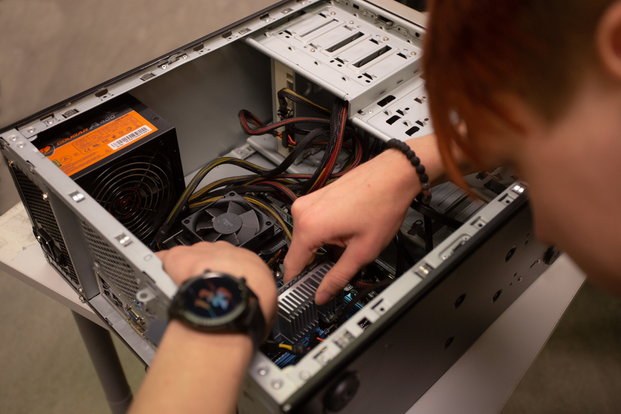 it-tukihenkilöksi opiskeleva korjaamassa pöytätietokoneen keskusyksikköä