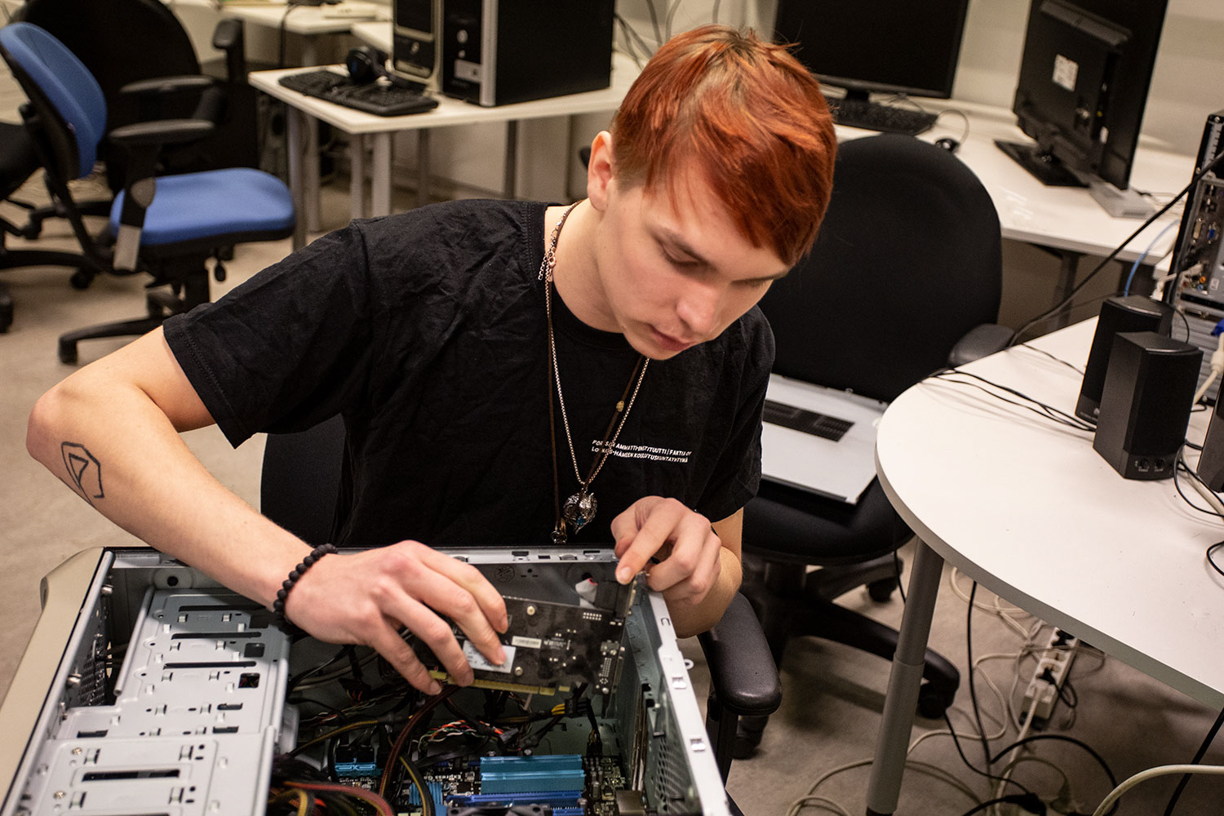 it-tukihenkilöksi opiskeleva korjaamassa pöytätietokoneen keskusyksikköä
