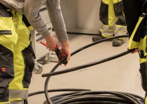 sähköpuolen opiskelija katkaisemassa johtoa