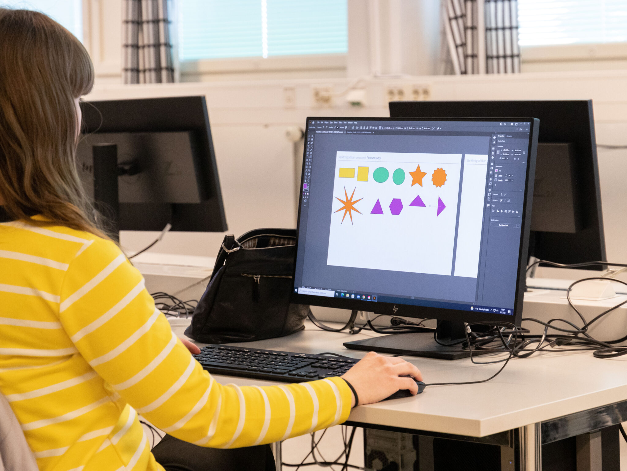 Graafisen suunnittelun opiskelija harjoittelee kuvioiden tekemistä tietokoneella